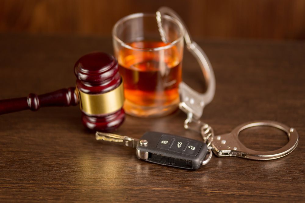 Whiskey glass, car keys, and gavel on a table
