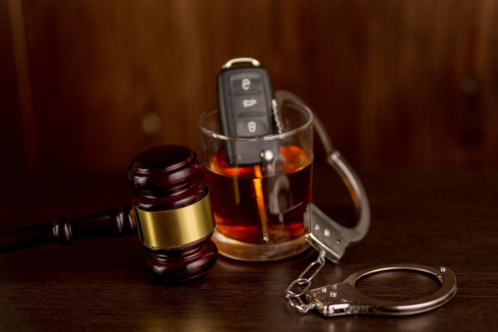 Gavel, whiskey glass, and handcuffs on a table