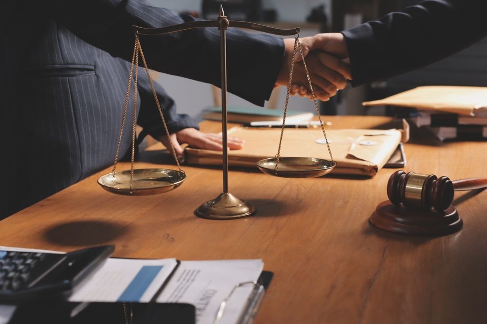 Justice scale and gavel as colleagues shake hands